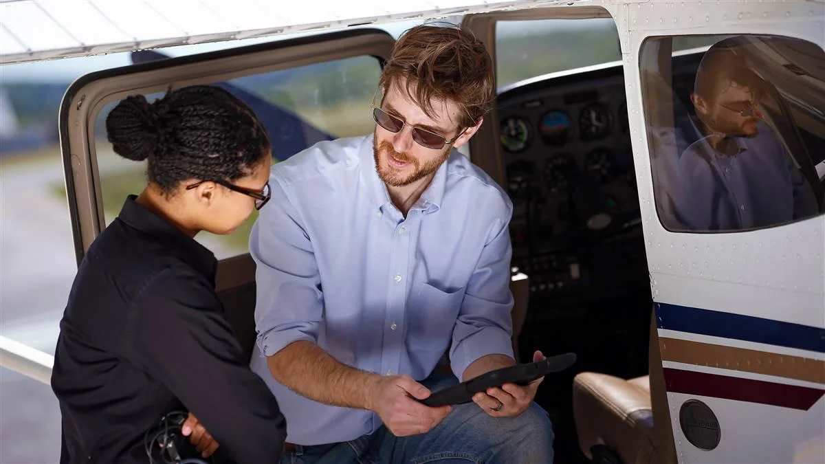 Flight instructor and student standing beside a training aircraft